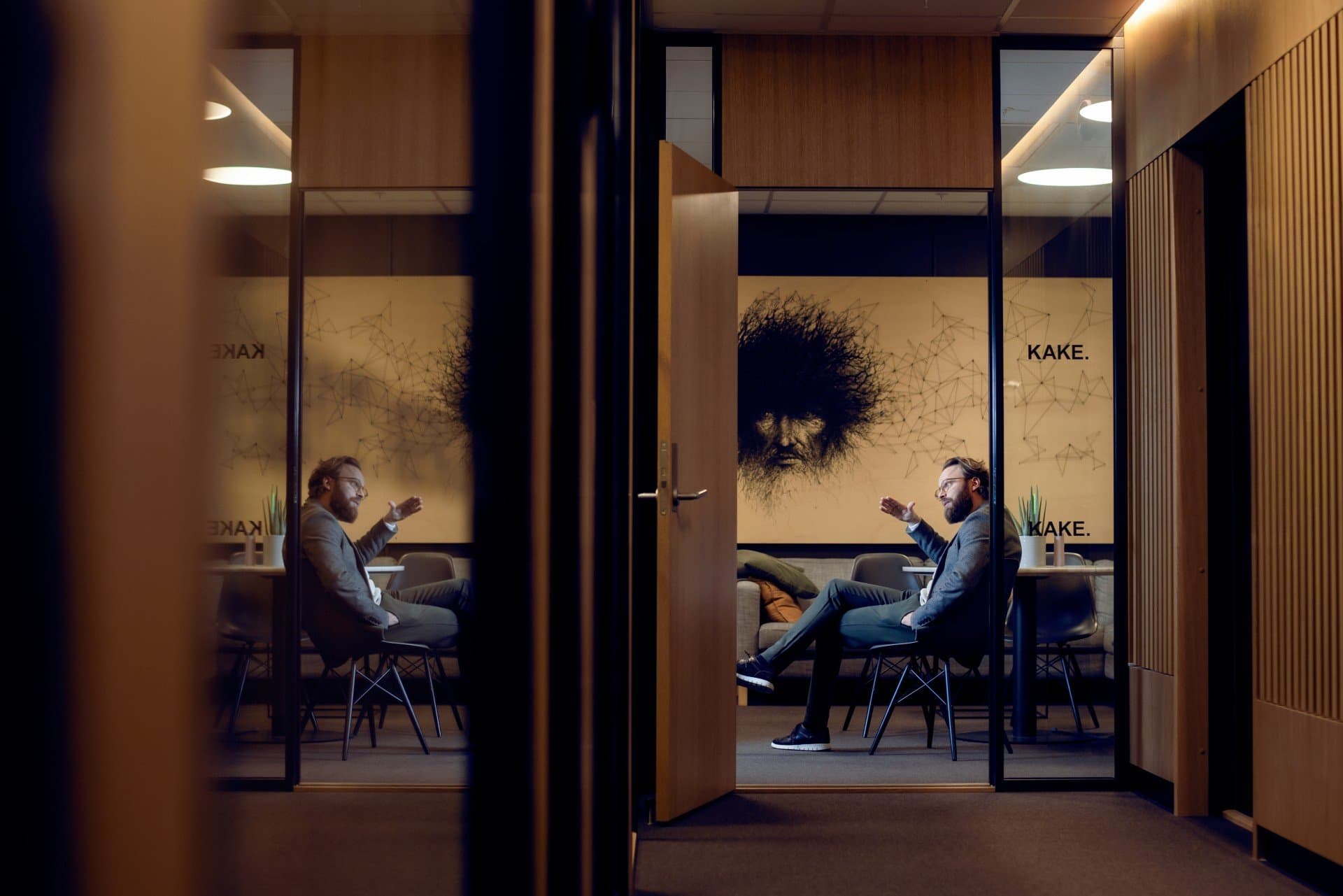 Man som sitter i ett konferensrum och pratar med en kollega. 